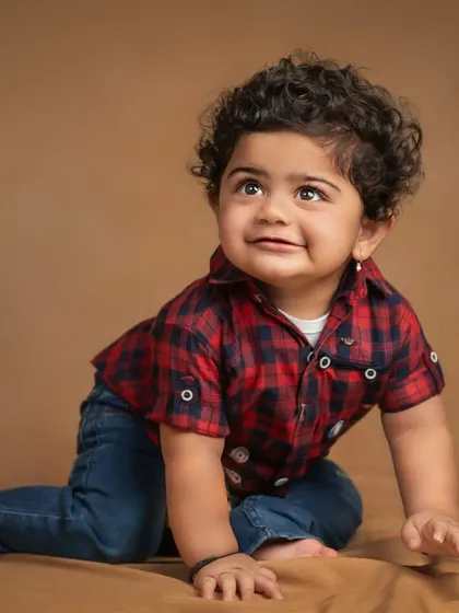 A handsome little boy with curly hair, crawling and looking up with a curious smile. This studio shot captures the joy of exploration.
