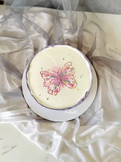 I love how this hand-drawn butterfly turned out. The intricate details and colorful sprinkles on a simple lilac and white cake make it a piece of edible art.