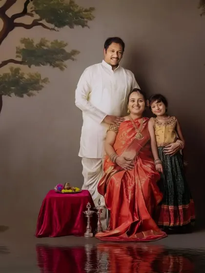 A regal family maternity portrait. The expecting mother is seated like royalty, surrounded by her family in a beautifully painted, traditional Indian setting.