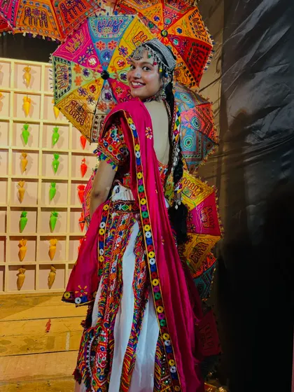 A smiling shot from behind, giving a great view of the colorful umbrella and the traditional parandi hair accessory.