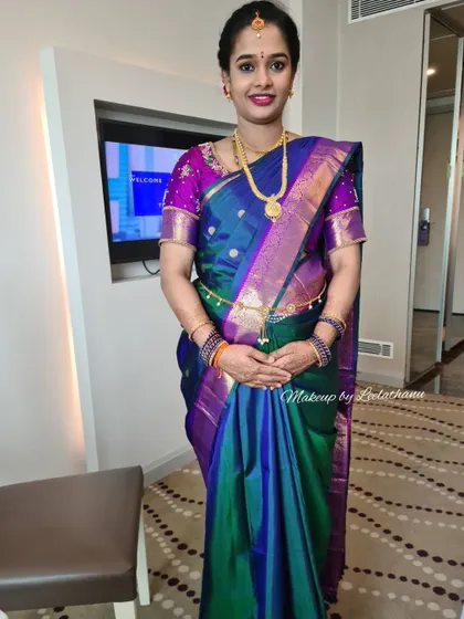 A full-length view of a client at her Srimantham. The makeup is flawless, and her peacock-blue and purple saree is draped perfectly to accommodate her baby bump.