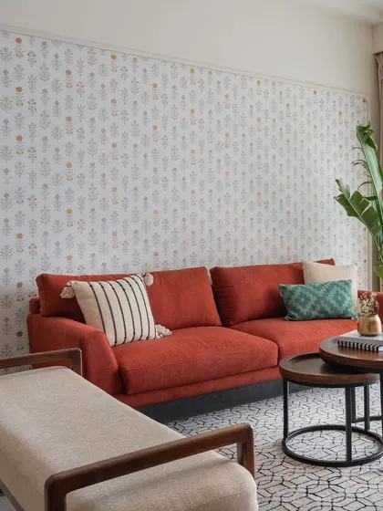 The 'Living life in Colour' living room features a vibrant wine-colored sofa set against an arched niche with character-rich wallpaper. The space is bright, cheerful, and full of personality.