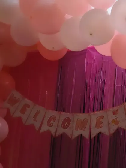 A close-up of a "Welcome Baby" banner against a pink shimmer curtain. This detail is part of a larger home decoration setup, perfect for celebrating a newborn's arrival.