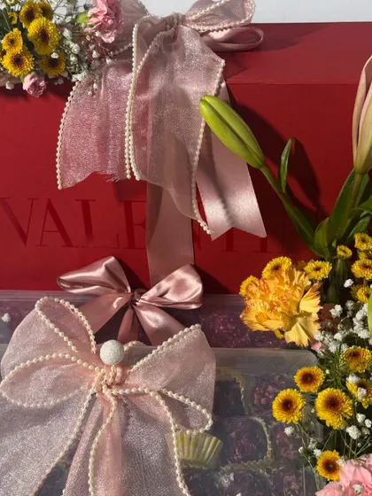 A closer look at the details of our luxury birthday hamper. Notice the Valentino box and the delicate pearl-studded ribbons that add a touch of opulence to the fresh flower arrangement.