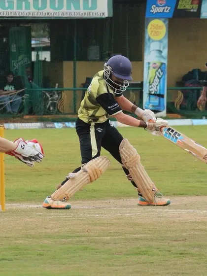 An action shot capturing a batter playing a shot with the wicketkeeper in position.