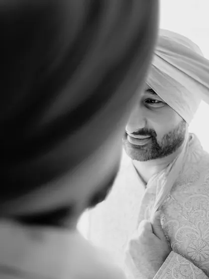 A candid, black and white shot of the groom getting his turban tied. The genuine smile and the intimacy of the moment make it a special memory.