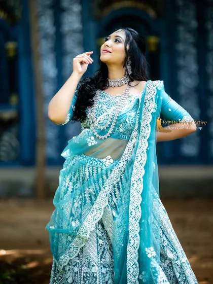 This upward-looking pose highlights the detailed work on the blouse and the sheer net dupatta of the blue lehenga.