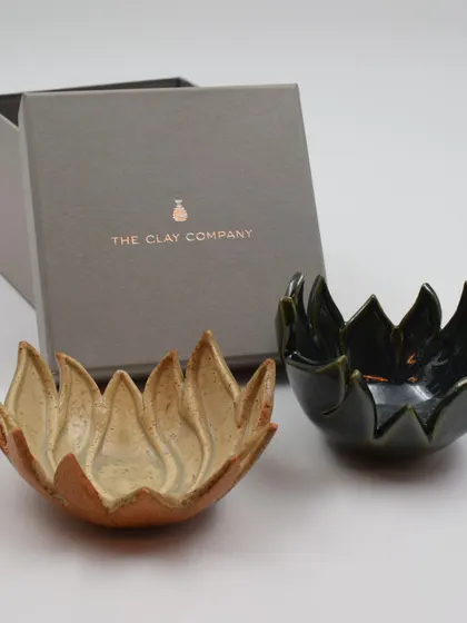 A set of two lotus bowls, one in a natural speckled glaze and the other in a deep green, shown with their custom gift box. This makes for a perfect, ready-to-give present.