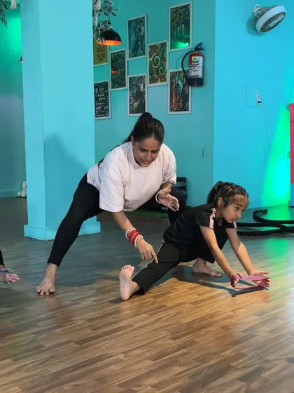 Guiding a student through a side lunge stretch. Personal corrections are key to helping young dancers understand how to engage the right muscles.