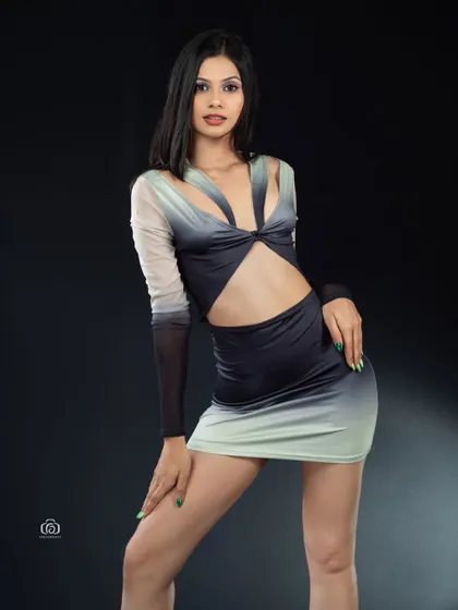 A full-length view of a modern, cutout dress against a stark black background. The studio lighting is focused on the model, making the colors of the dress and her confident stance the main features.