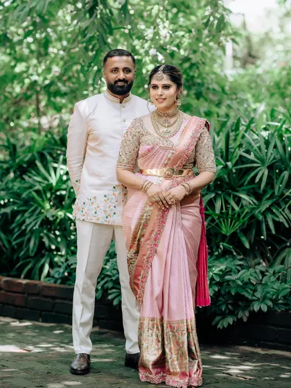 A full-length shot of my husband and me in our coordinated baby shower outfits. My pink saree is complemented by his elegant cream and white embroidered ensemble.