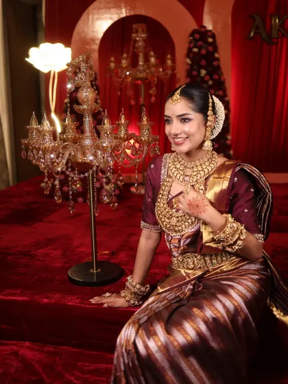 Seated in a regal setting, this bride's look is completed by a beautiful candelabra and a rich, red backdrop.