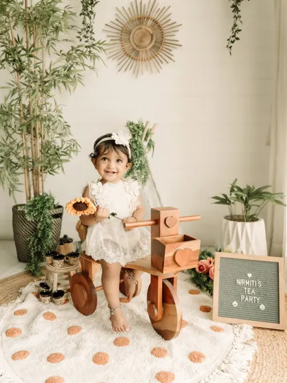 A happy smile from the birthday girl on her wooden tricycle, surrounded by boho-chic decor.