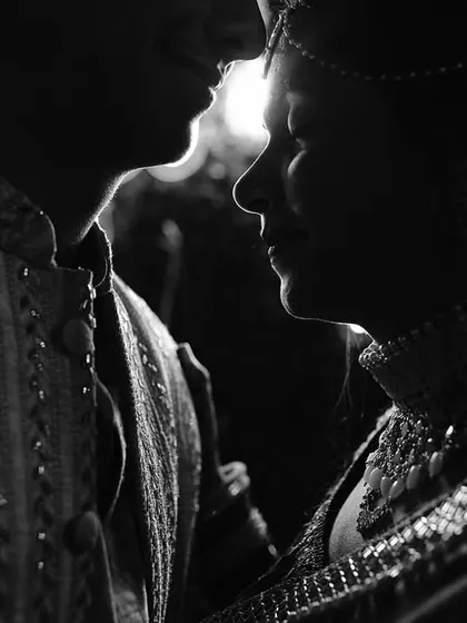 A moody and intimate black and white portrait. The close-up focuses on the couple's profiles, creating a sense of closeness and quiet connection.