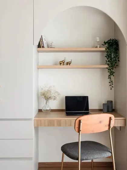 This study space is all about seamless integration. I designed an arched niche with wooden shelves for books and decor, built into a wall that also houses a full-height wardrobe with elegant gold handles.