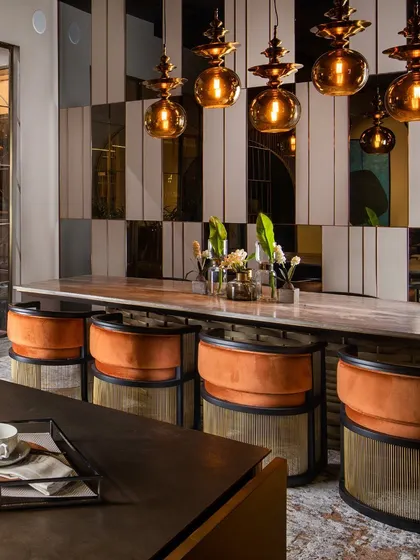 This angle highlights how the reflective surfaces in the wall panelling play with the ambient light from the pendant fixtures, creating a dynamic and inviting atmosphere perfect for a modern dining experience.