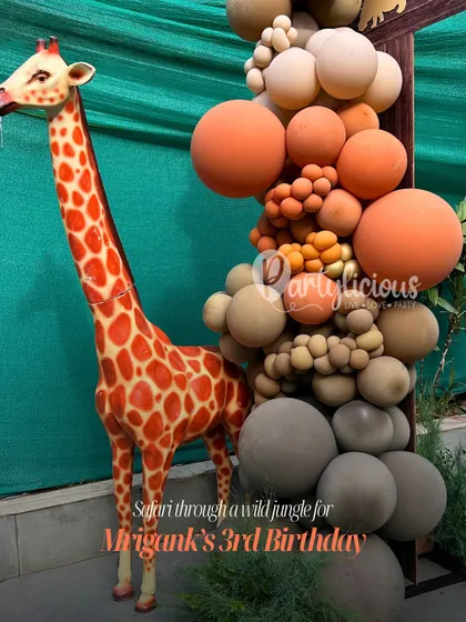 Safari through a wild jungle for Mrigank's 3rd Birthday. A life-sized giraffe prop stands next to a beautiful balloon arrangement in earthy tones.