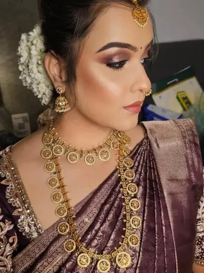 A side profile of the model, showing the kasu haram, jhumkas, and maang tikka.