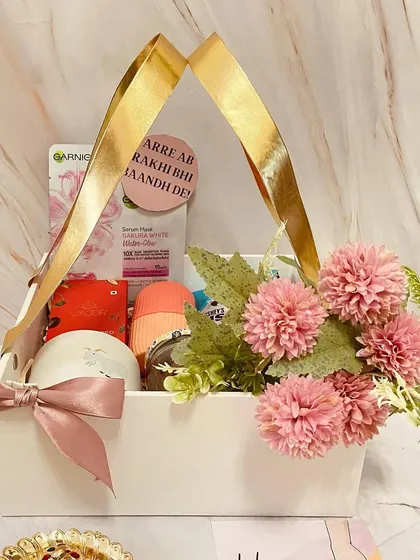 A beautiful white basket hamper for a sister, filled with skincare products and adorned with pink flowers.
