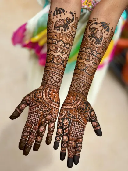 A straight-on view of the umbrella elephant design, showing the rich, dark henna application.