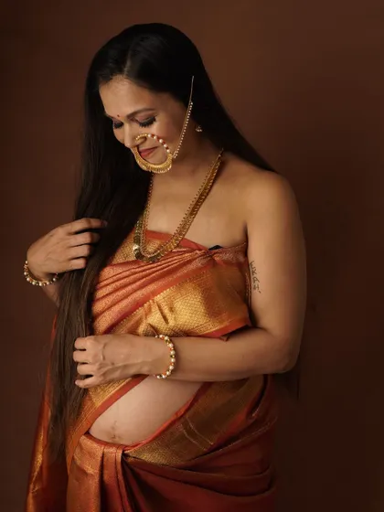 This is a professional maternity photo of me, draped in a traditional saree. It captures the beauty and sacredness I felt during my pregnancy, a feeling I try to share in all my classes.