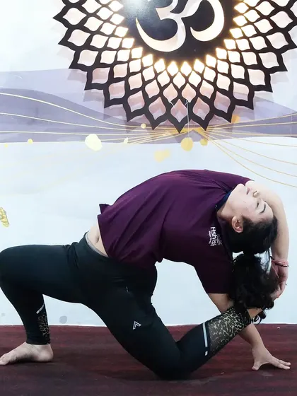 A deep backbend in a kneeling position, showing advanced flexibility in the spine and quadriceps.