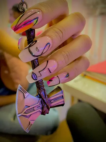 A unique, abstract design on long coffin nails. The sheer base is decorated with black line art and pops of neon color, shown here held with a Thor's hammer keychain.