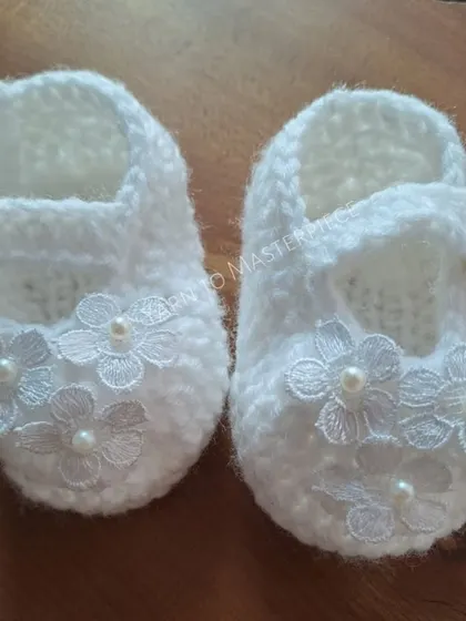 These white Mary Jane-style booties are perfect for a baptism. They are adorned with delicate lace flowers, each centered with a tiny pearl for a classic look.