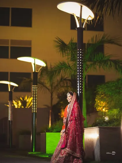 A stylish night portrait of the bride. She stands elegantly by a modern lamppost, the lighting creating a beautiful and contemporary bridal shot.