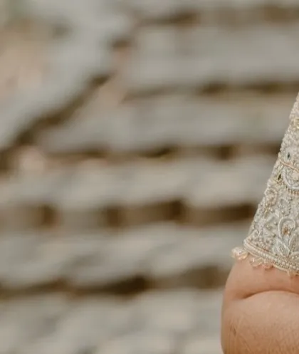 A macro detail shot of the intricate embroidery and beadwork on a bride's blouse sleeve. Our photography ensures that no small detail of your outfit is overlooked.