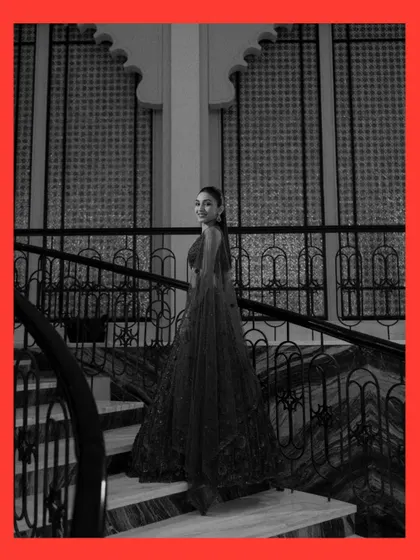 A timeless black and white bridal portrait on a grand staircase. The bride's glance back at the camera is both elegant and engaging, highlighting the beautiful silhouette of her gown.