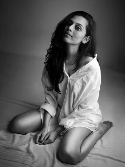 A classic black and white portrait. The simplicity of the white shirt and the soft, diffused light create a timeless image that focuses purely on the subject's natural beauty and mood.