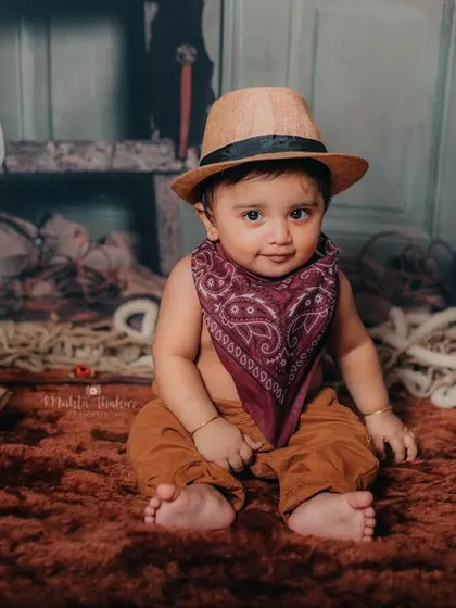 Howdy, partner. This 6-month-old cowboy is ready for his Wild West adventure, complete with a hat and bandana.