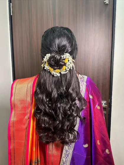 A Maharashtrian bridal look with a half-updo, adorned with fresh yellow flowers and a traditional ear chain. It's a beautiful blend of modern and traditional styles.
