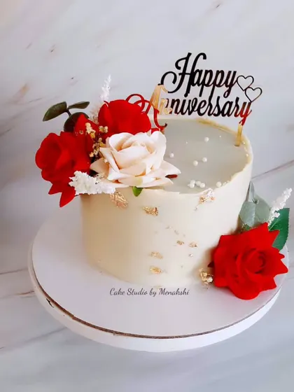 A lovely anniversary cake decorated with red and white roses and touches of gold leaf. The 'Happy Anniversary' topper completes this romantic, no-fondant design.