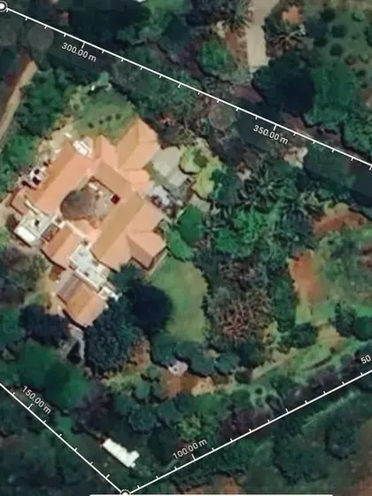 An aerial view of a sustainable farmhouse project. This image shows the master plan in action, with the main house nestled within a large, green plot focused on water management, rainwater harvesting, and planting native trees to achieve a net-zero impact.