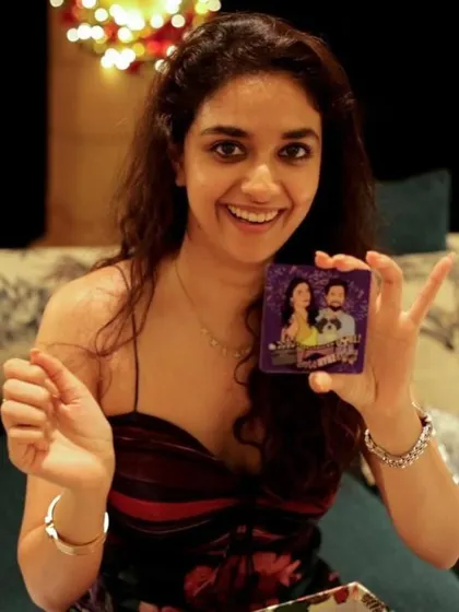 The bride, Keerthy Suresh, happily holding a personalized chocolate bar from the return gift hamper I curated for her wedding guests.