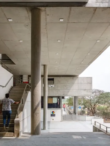 A student ascends a staircase in the open, naturally lit corridor of the VIT School of Architecture.