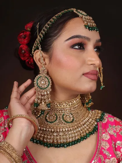A side profile of the bridal look, showing the beautiful hair bun with red roses and the intricate jewelry.