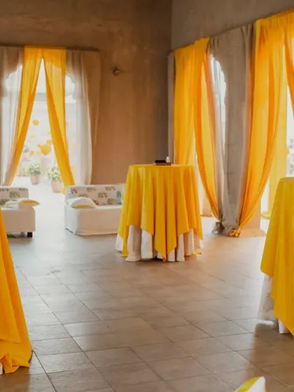 Bright yellow drapes bring a pop of color to this elegant indoor space, creating a sunny and festive atmosphere for a pre-wedding event.