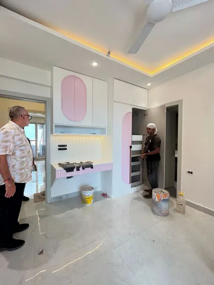 Here I am inspecting a custom-built wardrobe and study unit in a children's bedroom. The design features playful pink and white tones with unique curved cabinet doors.