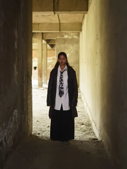 An edgy, high-fashion look in a raw, industrial hallway. The composition uses leading lines to draw the eye directly to the model.