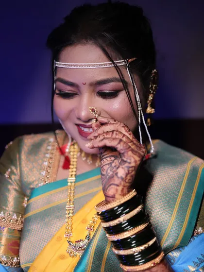 Another shot of the bride adjusting her nath, showing off her mehndi and green bangles.