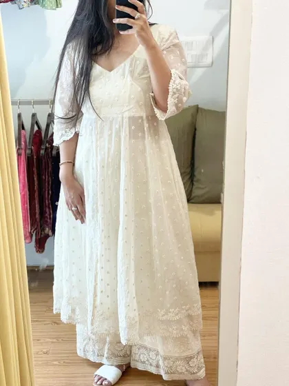 A mirror selfie showing our white cotton Angrakha dress. This piece features delicate all-over threadwork detailing and is paired with matching palazzos, offering a look that is both traditional and contemporary.