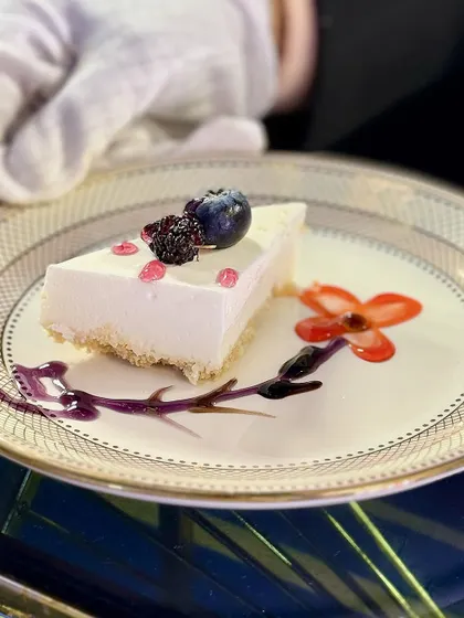 A slice of pure, creamy indulgence. Our classic Philadelphia Cheesecake is crafted for a silky-smooth, melt-in-your-mouth texture, served here with artistic sauce work and fresh berry toppings.