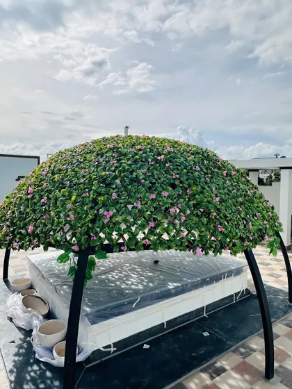 This is a custom-built rooftop gazebo I designed, covered entirely in artificial flowering vines. It provides a beautiful, shaded seating area and demonstrates how we can create unique, large-scale green structures for any outdoor space.