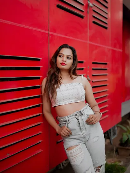 A classic street fashion portrait. The model's relaxed pose against the bright red wall creates a simple yet powerful image that highlights her style.