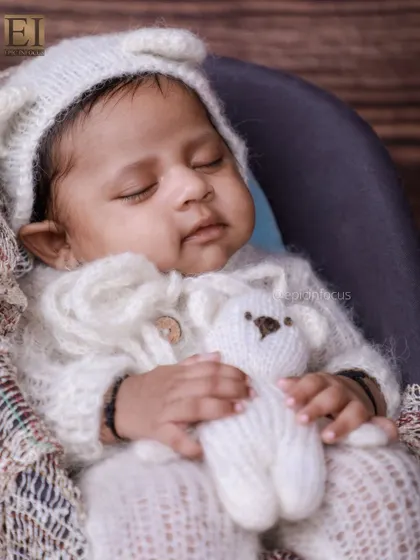 A sweet moment with the baby holding a tiny teddy bear, part of our vintage-themed photoshoot. These small details add a touch of innocence and charm.