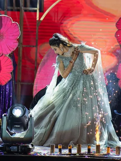 A captivating shot of a bride's solo performance, enhanced with stage sparklers and a backdrop of vibrant prop flowers. We ensure every moment is picture-perfect.