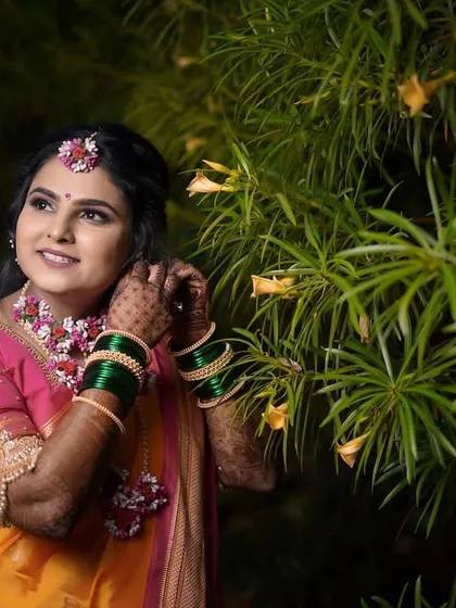 A candid shot of the bride adjusting her floral earring. This portrait captures a natural, unposed moment, highlighting the details of her Haldi ceremony look.